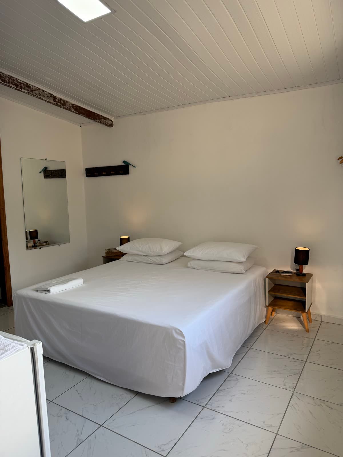 Suíte Mar: quarto amplo e claro com cama de casal e piso claro